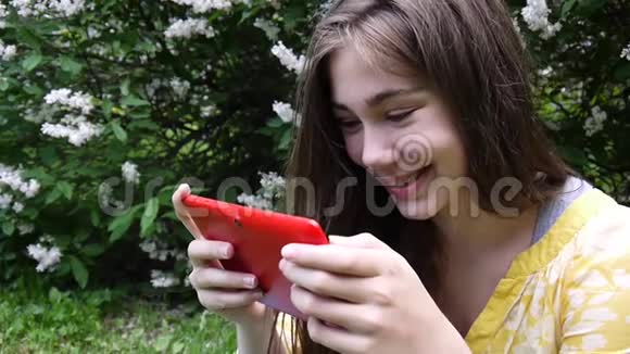 美丽的少年女孩带着平板电脑坐在公园的草地上静态相机的电影视频的预览图