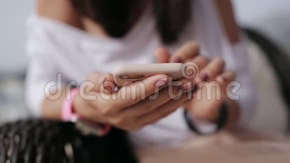 年轻女孩坐在餐桌旁的咖啡馆里使用智能手机视频的预览图