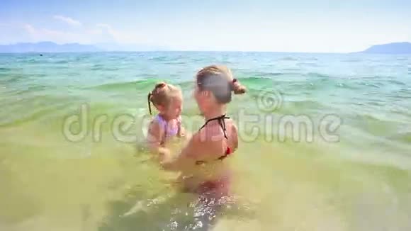 母亲高举小女儿在蔚蓝的海洋视频的预览图