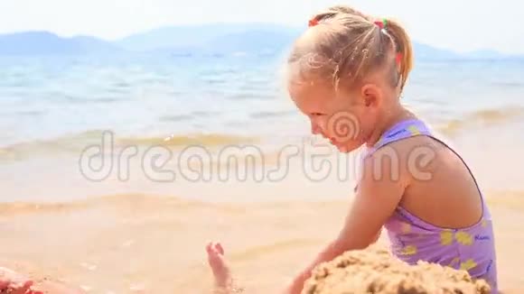 碧海滩上的金发小女孩沙堡视频的预览图