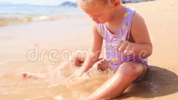 碧海滩上的金发小女孩沙堡视频的预览图