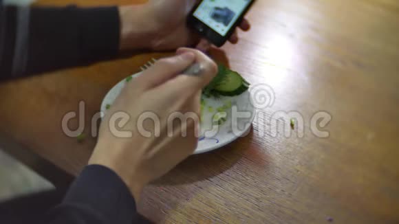 男人用洋葱和迪尔智能手机吃土豆互联网社交媒体传统的俄罗斯室内美食视频的预览图