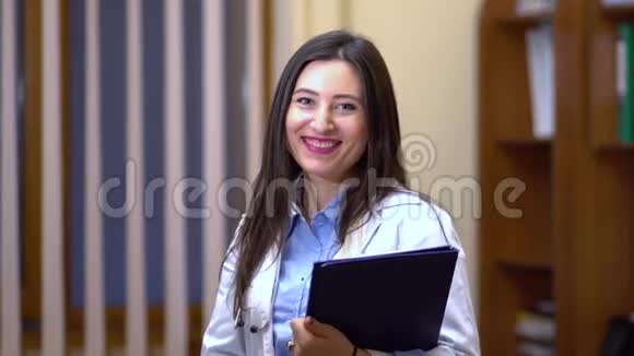 女医生看着摄像机微笑着手里拿着平板视频的预览图