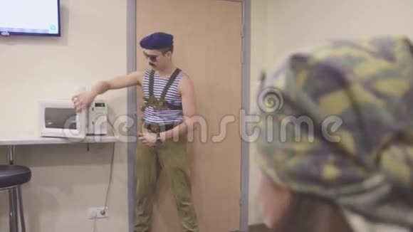 男士穿着海军衬衫和帽子太阳镜打开微波炉手里拿着刀说话超现实主义视频的预览图