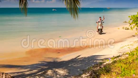 男子驾驶摩托车到棕榈浪手海滩视频的预览图