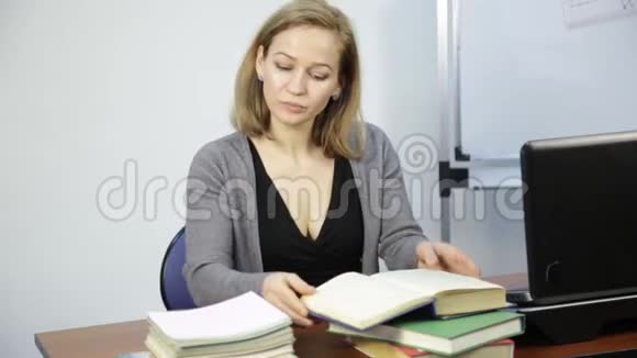 女老师在笔记本电脑前检查教室里的作业视频的预览图