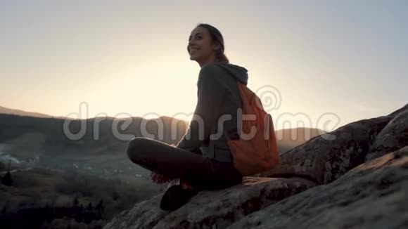 在日出的背景下女人坐在悬崖边视频的预览图