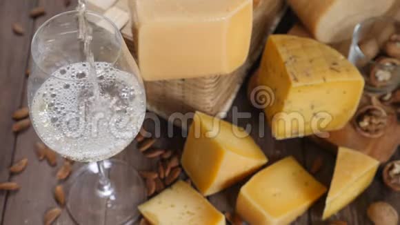 食品艺术不同种类的奶酪在木制背景上排列得很漂亮上景白葡萄酒正被倒入视频的预览图
