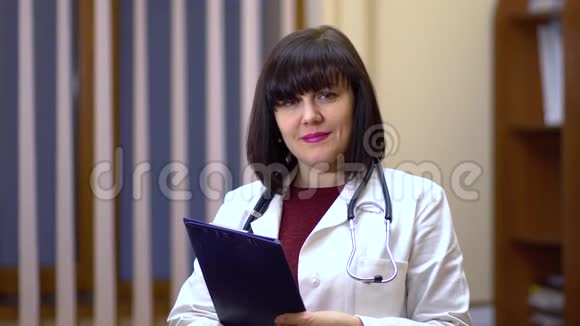 女医生看着摄像机微笑着手里拿着平板视频的预览图