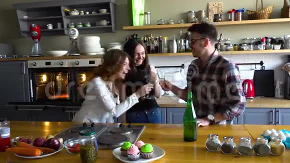 两个女孩和男孩在厨房庆祝生日并在厨房里用香槟庆祝生日视频的预览图