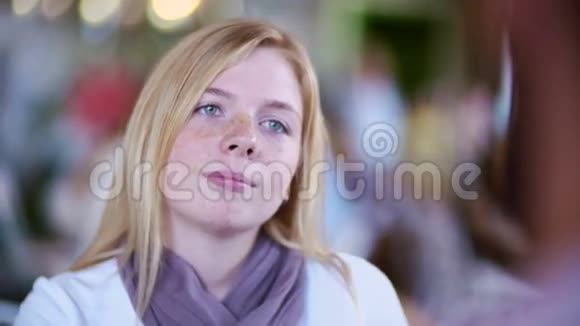 年轻漂亮的金发女孩坐在咖啡馆的桌子旁和男朋友约会听他说话视频的预览图