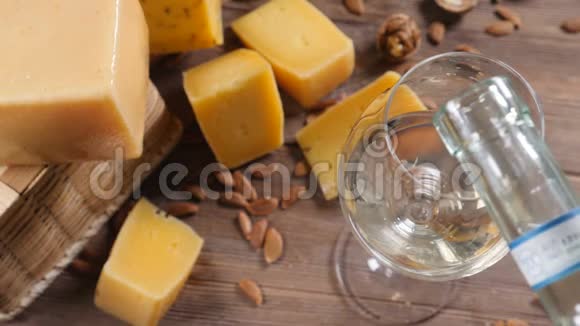 食品艺术不同种类的奶酪在木制背景上排列得很漂亮上景白葡萄酒正被倒入视频的预览图