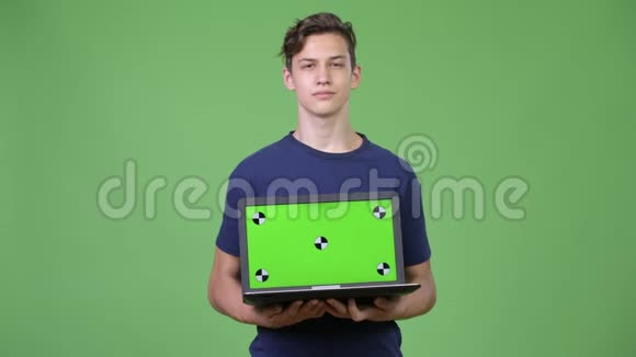 年轻英俊的十几岁男孩展示笔记本电脑视频的预览图