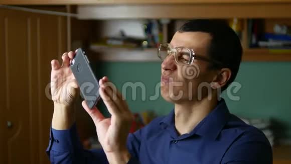 男人眼镜使有趣的自拍手机室内智能手机视频的预览图