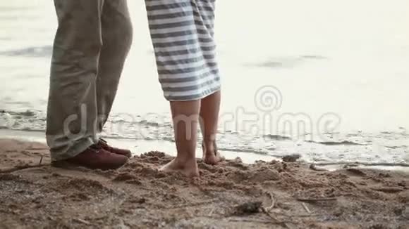 沙滩上年轻夫妇的腿特写女孩掉进水里视频的预览图