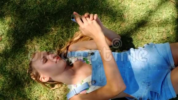 漂亮的女孩在公园里发短信视频的预览图