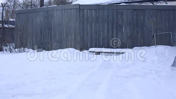 雪夜后工作在一个寒冷的雪天早晨一个拿着铲子把雪从院子里移走的人视频的预览图