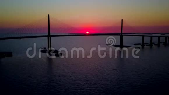 美丽温暖的黄昏日落在巨大的公路上钢桥穿过平静的蓝海在4k空中无人机海景视频的预览图