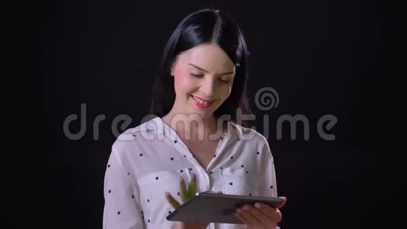 美丽迷人的年轻女子展示着带有色度和微笑的平板电脑被孤立在黑色背景上视频的预览图