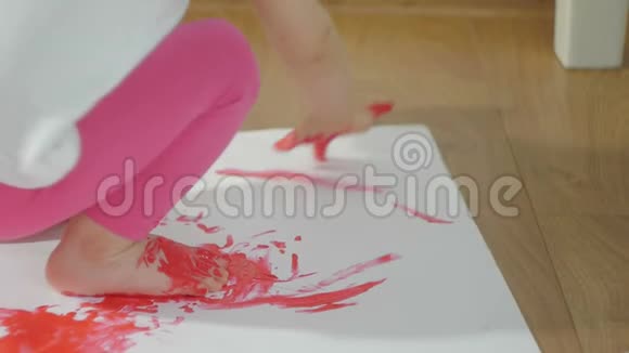 一个小女孩的特写镜头她的手沾满了红色的颜料她的手指在一张大白纸上视频的预览图