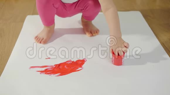 一个小女孩的特写镜头她的手沾满了红色的颜料她的手指在一张大白纸上视频的预览图
