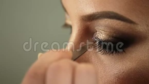 美容沙龙化妆师将睫毛贴在金色眼睛上视频的预览图
