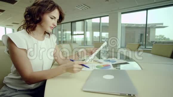 女人用图表和笔记本电脑工作视频的预览图