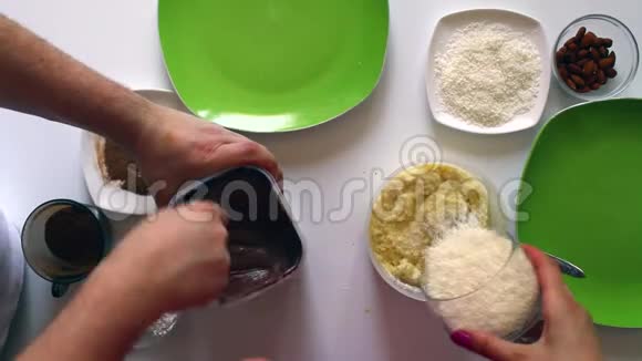 一对已婚夫妇用炼乳椰子刨花和杏仁准备糖果视频的预览图