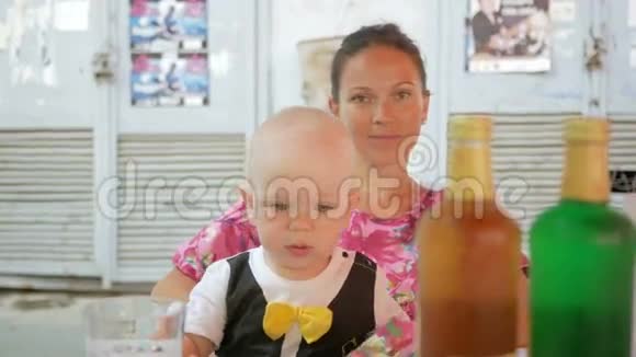 妈妈和宝宝穿着一件漂亮的裙子和蝴蝶在街上的咖啡馆里吃饭有青黄柠檬水的银行视频的预览图