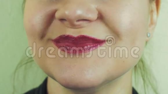 女人带着红色的柚子微笑在镜头中发音单词嘴巴牙齿空气亲吻视频的预览图