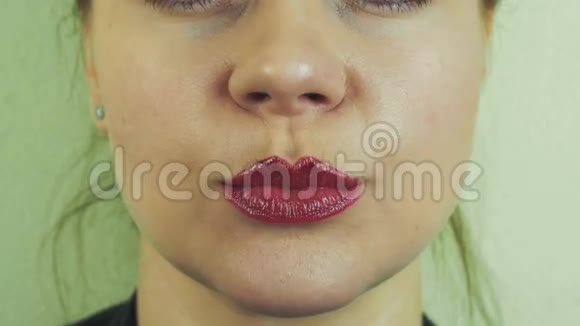 女人用手在镜头前从嘴唇上涂抹红色的蜜汁嘴巴微笑脸面视频的预览图