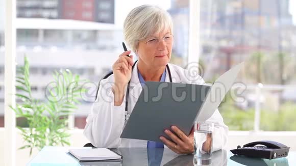 微笑着成熟的医生看着文件视频的预览图