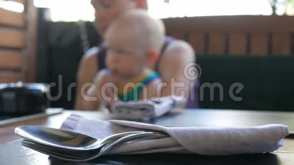 妈妈和宝宝走进咖啡馆等待点菜孩子和周围的人玩勺子和叉子在里面视频的预览图