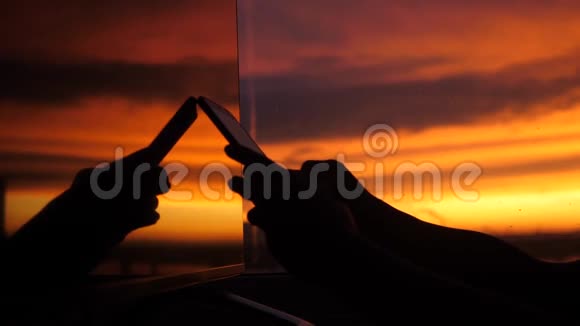 女的手在窗外倒影中的夕阳背景上使用智能手机3840x2160视频的预览图