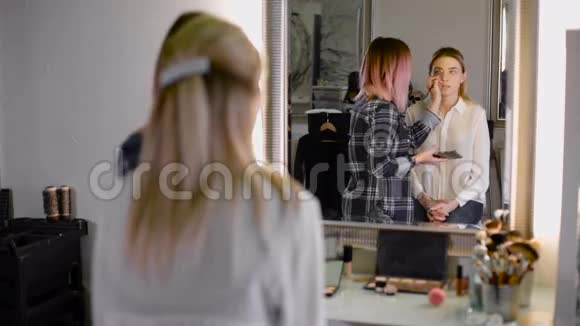 专业化妆师用画笔工作公认的设计师和镜子里的客户视频的预览图