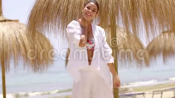 微笑着穿着鲜艳沙滩衣服的年轻女子视频的预览图