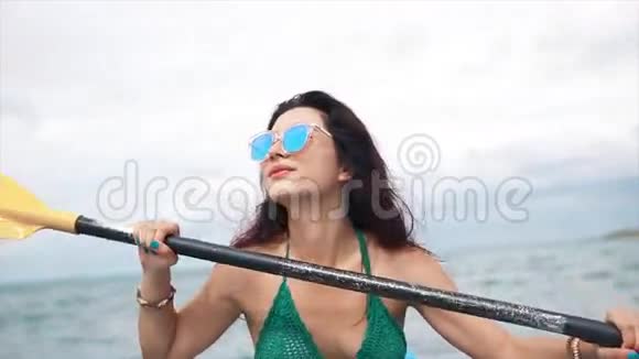戴墨镜的漂亮女孩在皮划艇上划船视频的预览图
