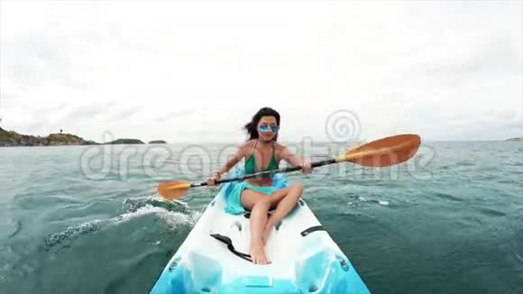 戴墨镜的年轻美女在皮划艇上划船视频的预览图