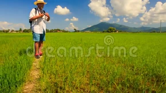 帽子里的老人镜头拍摄稻田对山视频的预览图