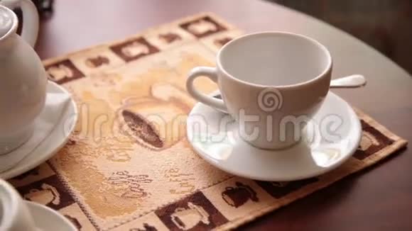女人手把热茶倒进咖啡桌上的白杯里视频的预览图