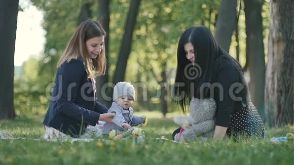 两个女人带着小男孩在绿色公园的封面上放松视频的预览图
