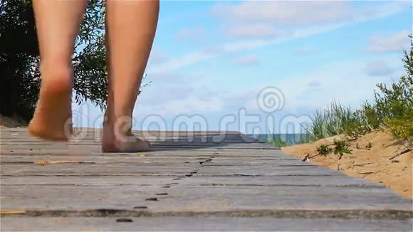 赤脚女孩走在海边的一个木墩上视频的预览图