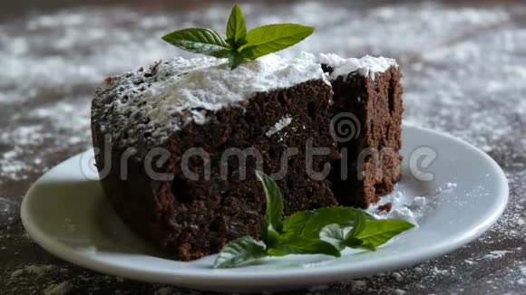 自制的烤巧克力巧克力蛋糕在一个用薄荷叶装饰的白色盘子上裹着糖粉叉叉视频的预览图