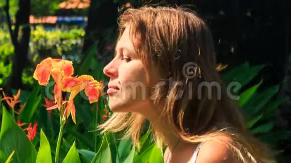 在公园拍摄热带花卉时金发女孩的气味视频的预览图