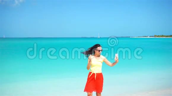 年轻女子在热带海滩度假时使用电话使用移动智能手机的游客视频的预览图