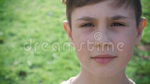 特写10岁男孩在春天或夏天绿色植物背景下的肖像视频的预览图