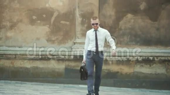 一位严肃的商人在一栋办公楼前拿着一个公文包系着领带视频的预览图