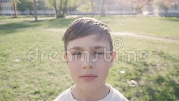 特写10岁男孩在春天或夏天绿色植物背景下的肖像视频的预览图