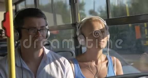 在公共汽车旅行中女人和男人听耳机音乐视频的预览图