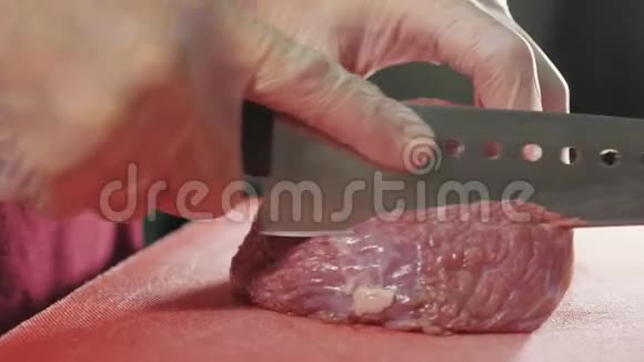 厨师用红板上的刀切生肉特写慢动作视频的预览图